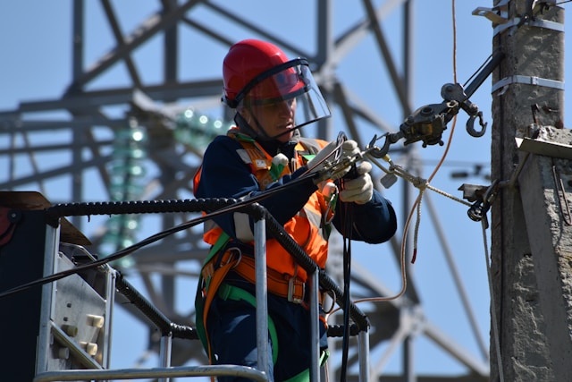 Superficial focus photo of a man fixing a steel cable